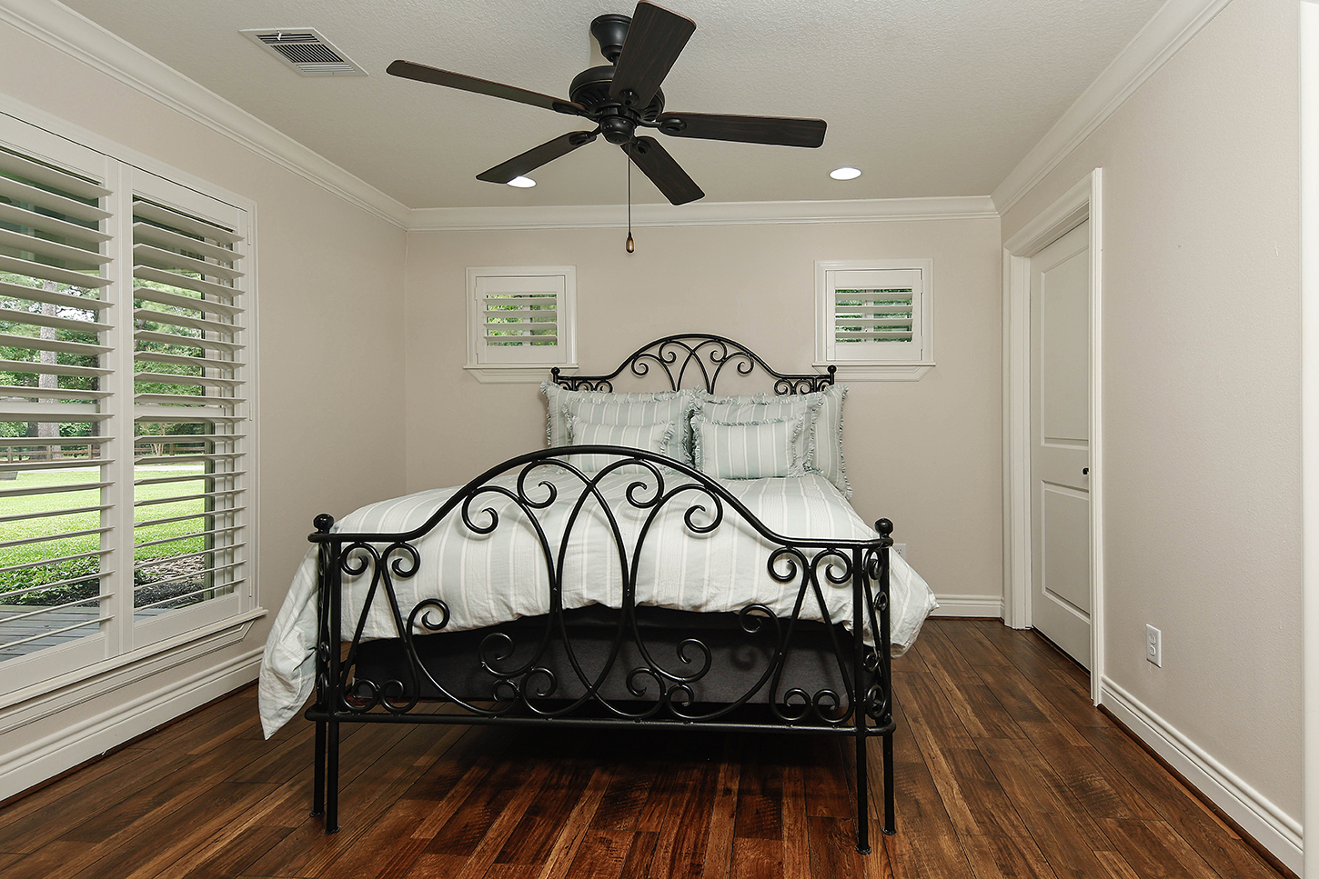 Bedroom with wrought iron bed and plantation shutters