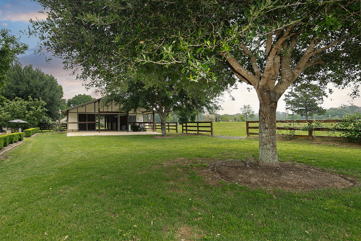 Barn and fenced pasture beneath mature oak trees