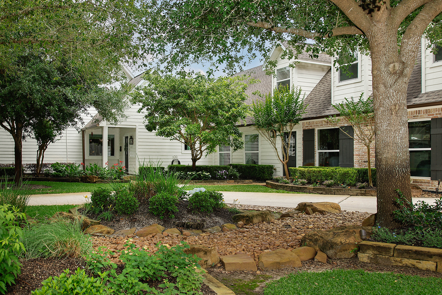 Landscaped courtyard entry framed by mature trees and stone beds