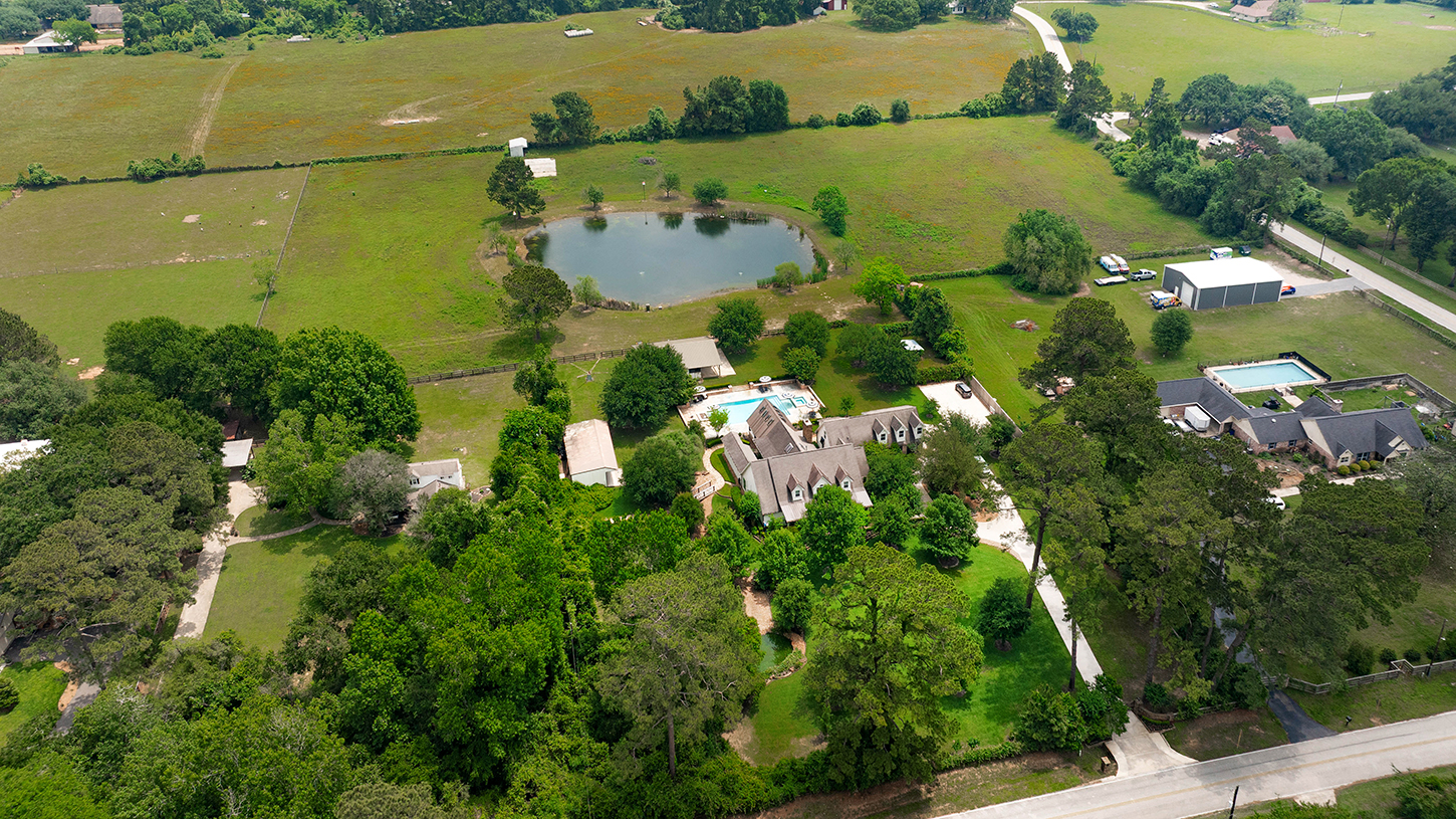 Drone view of the estate, pool, and pond surrounded by acreage
