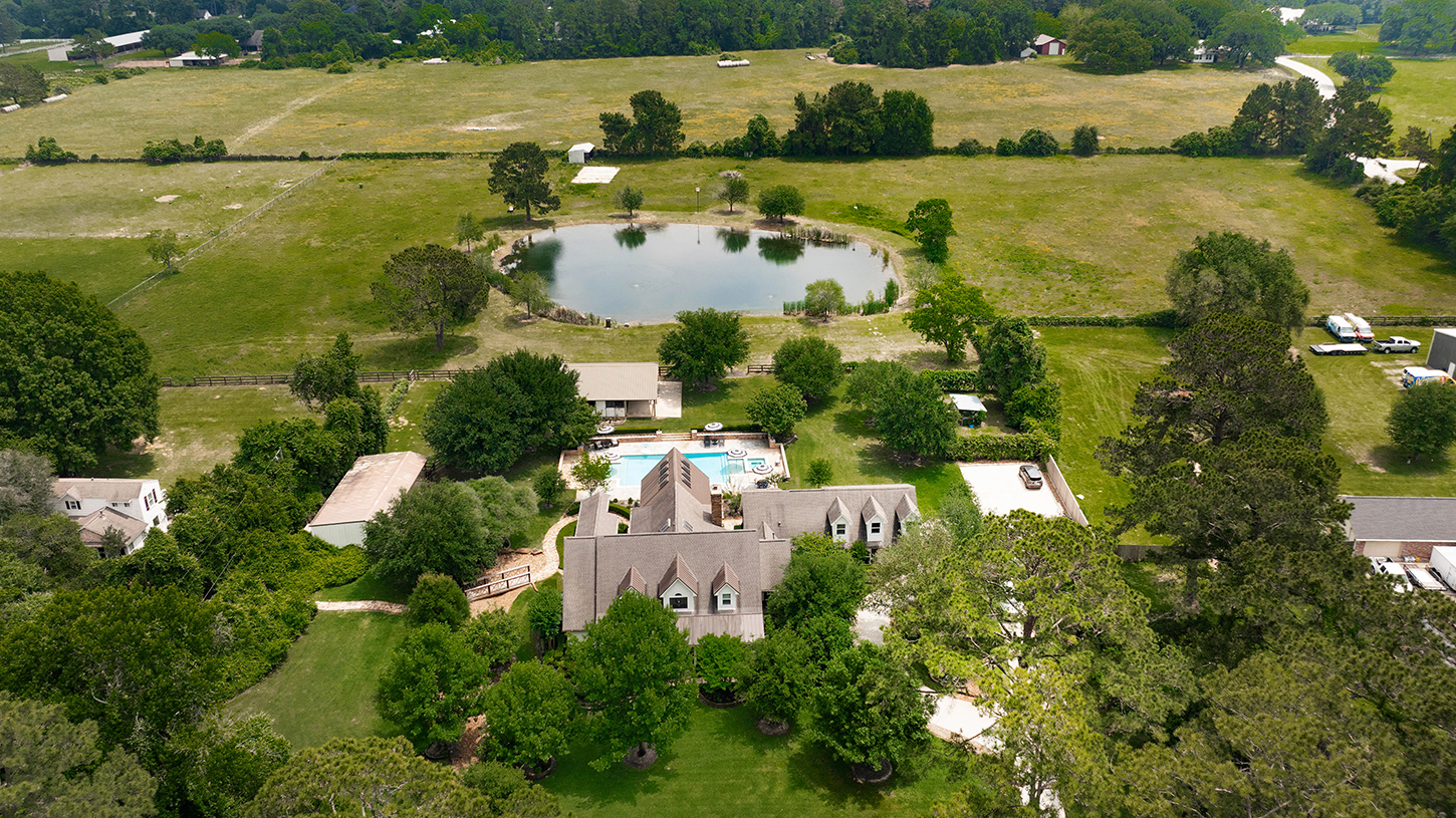 Aerial view of the estate with pool and pond across the pasture