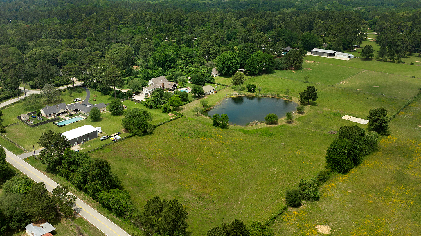 Wide aerial view of the full property with pond and acreage