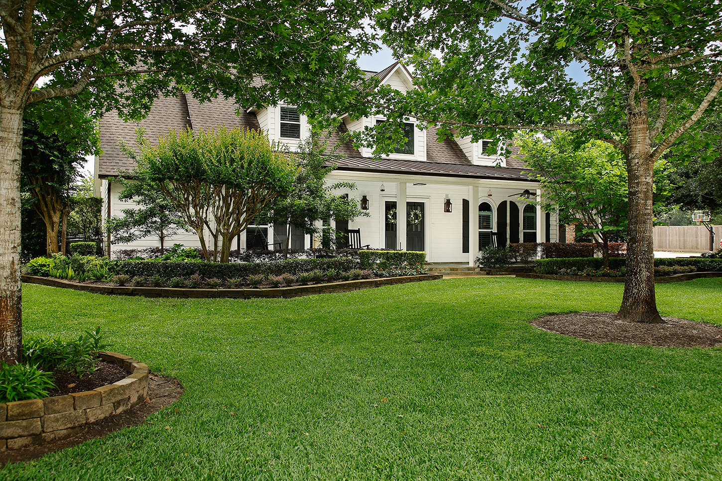 Wide front lawn facing the main residence beneath mature shade trees
