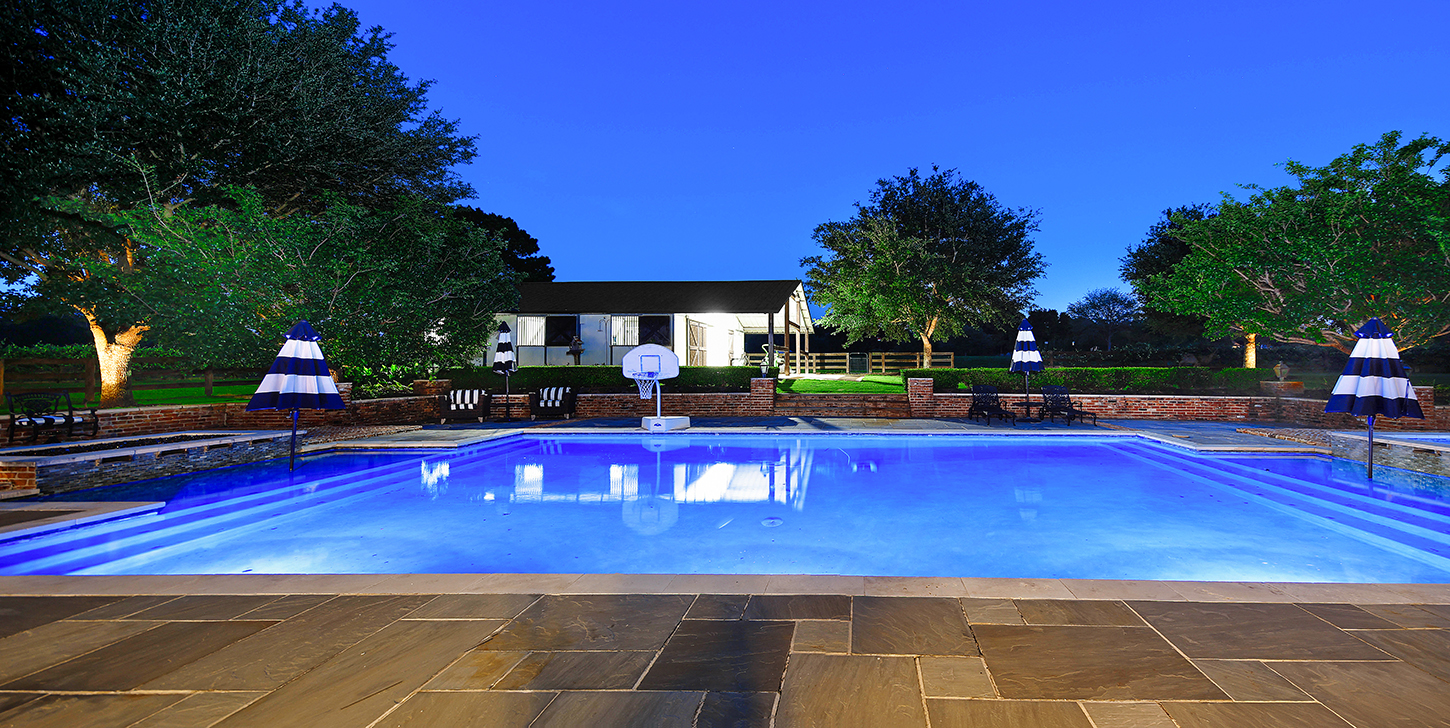 Pool with basketball hoop and stable view at twilight