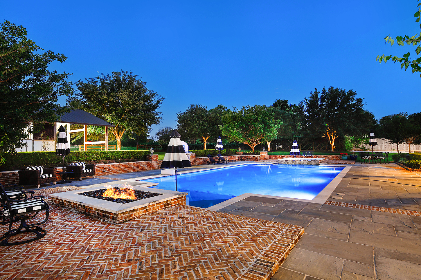 Pool, firepit, and pavilion lit up at twilight