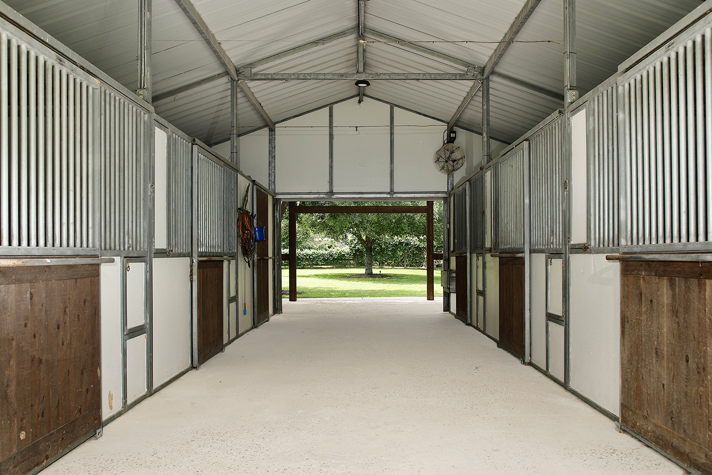 Center aisle inside the horse stable with multiple stalls