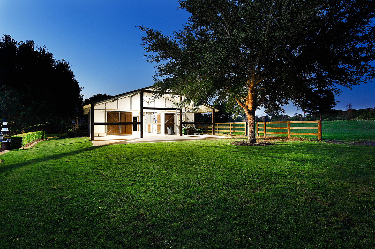Stable exterior illuminated at twilight with open lawn