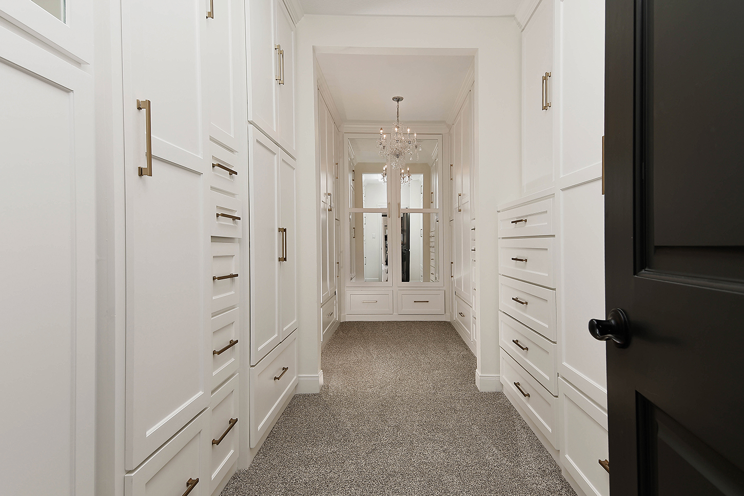 Custom walk-in closet with chandelier and built-in cabinetry