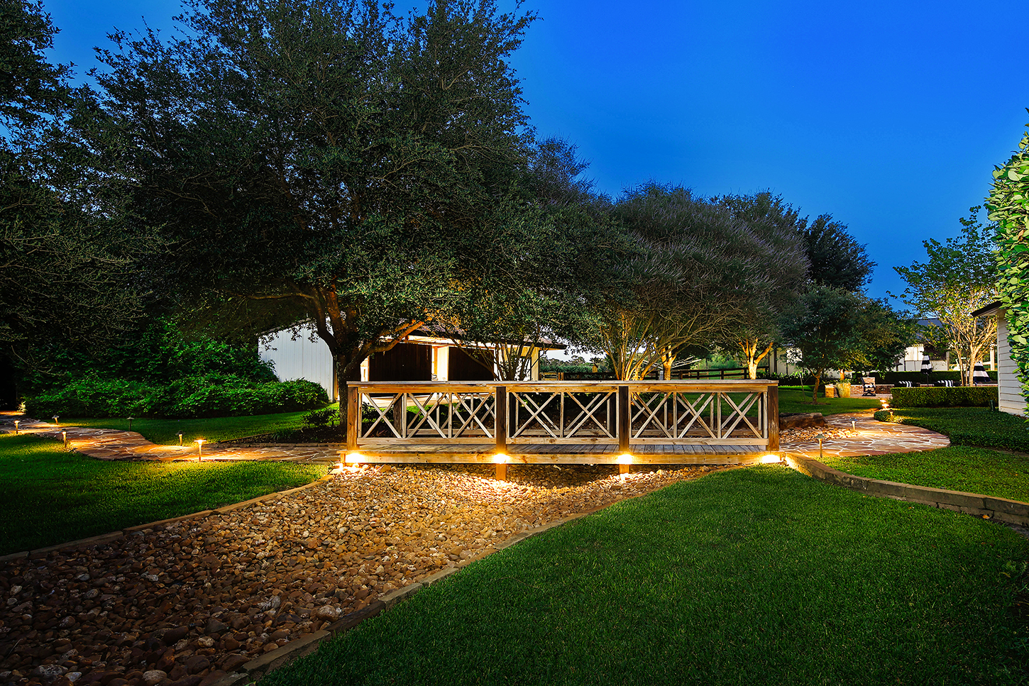 Lighted bridge and stone path at twilight near the main house
